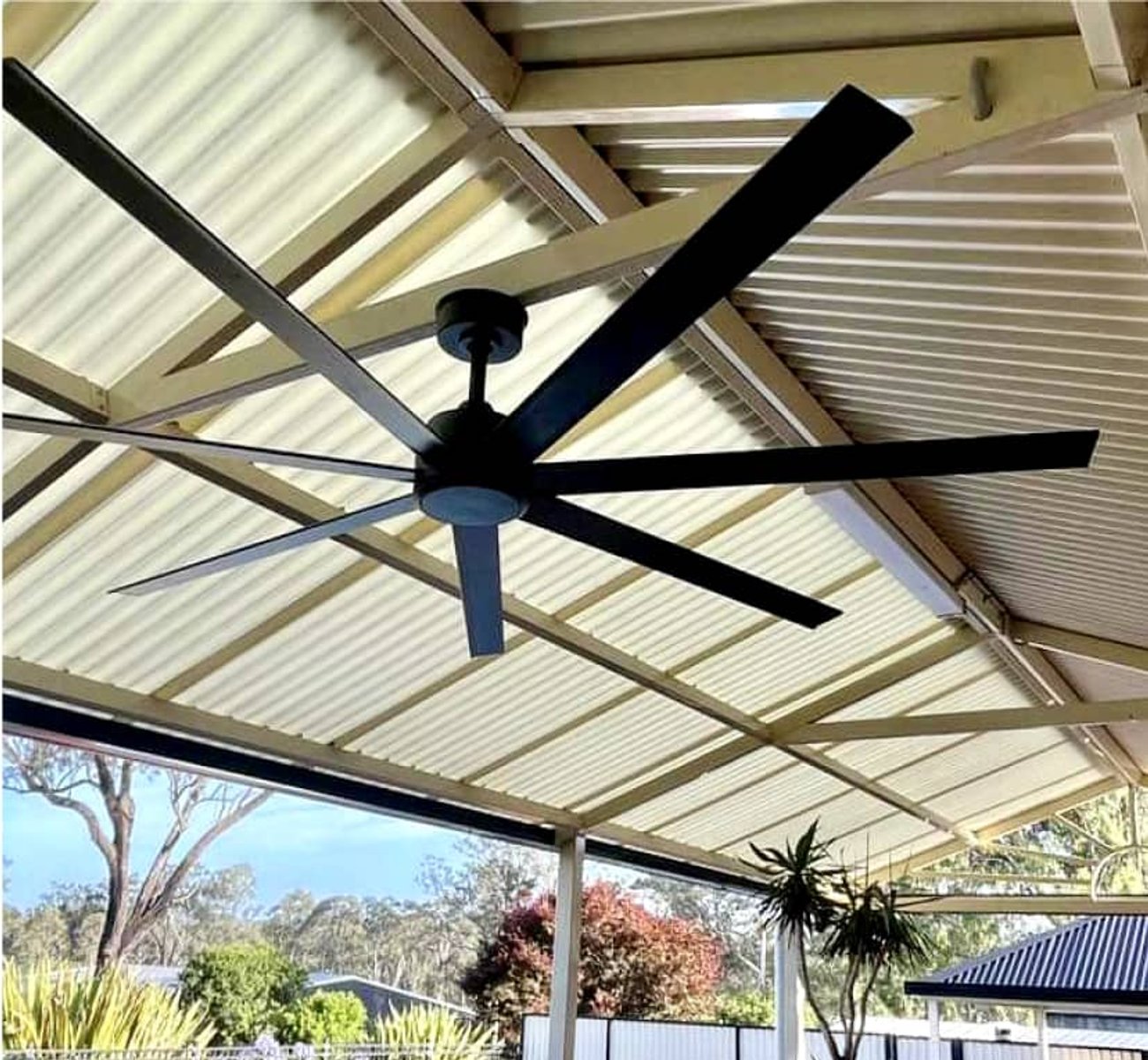 Electrician installing a ceiling fan in a modern living room